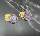 Celebrate February birthdays with this exquisite deep Purple Amethyst-inspired birthstone pendant, paired with your choice of a Aquarius or Pisces charm. This ½-inch round pendant features a floating disc elegantly stamped with the zodiac symbol and name, crafted in polished brass and sterling silver. 
Choose it as a standalone piece or pair it with an adjustable sterling silver cable chain (16, 18, or 20 inches) for a timeless look. For a modern touch, opt for a sterling silver or gold-filled papercl