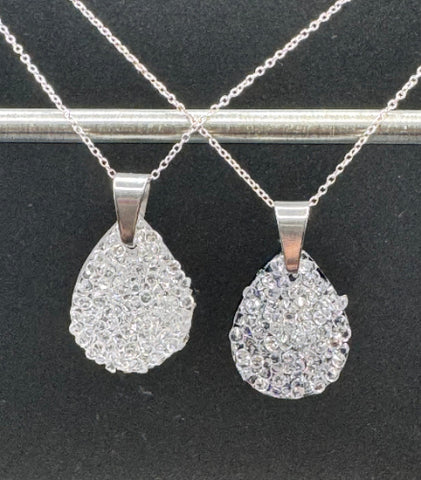 Two silver teardrop pendants on chains against a black background